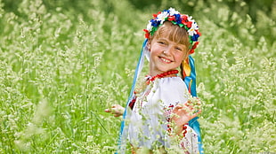 girl wearing assorted-color flower-accent headdress at the middle of green grass field HD wallpaper