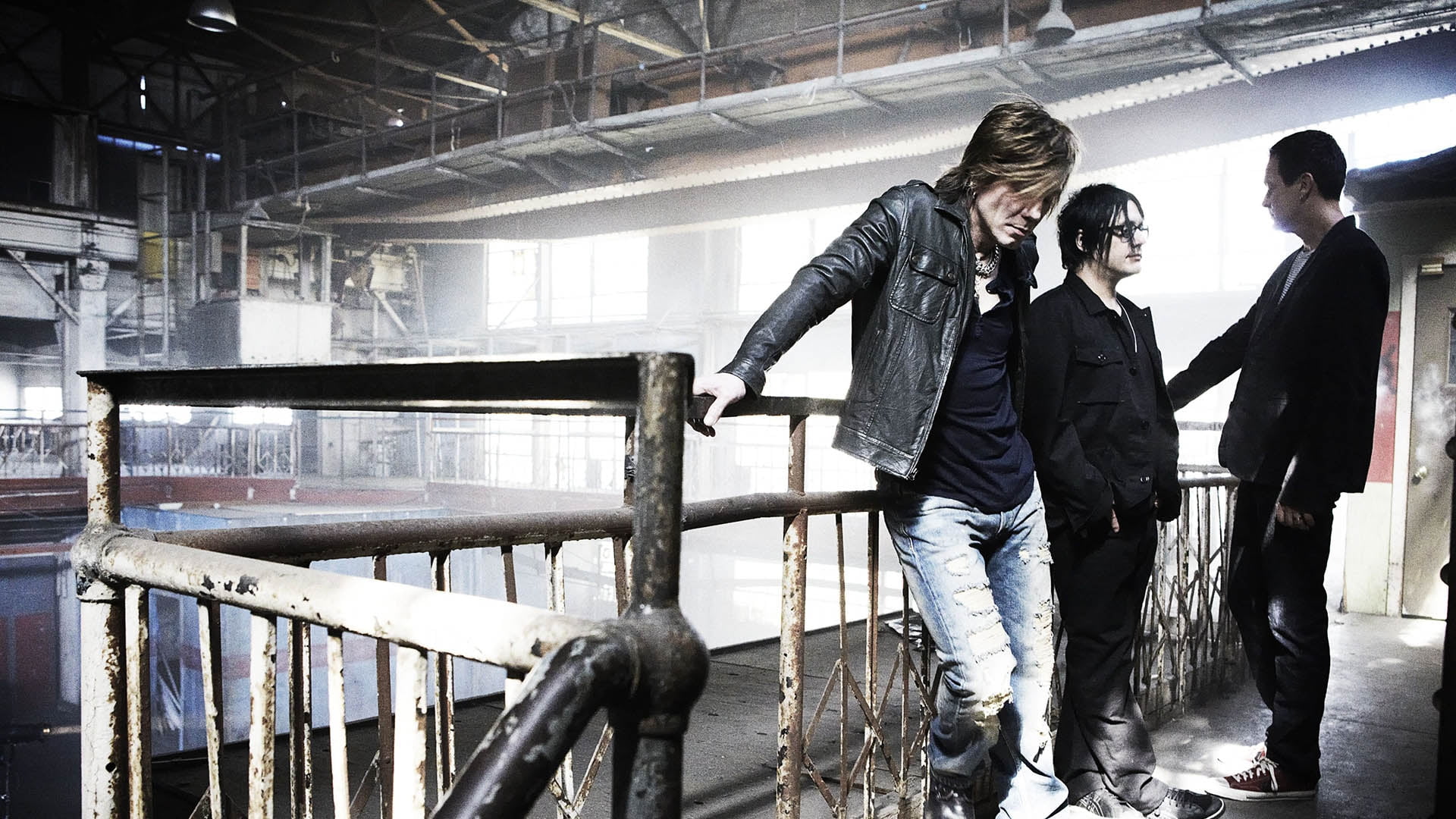 three men band members standing beside brown metal handrails