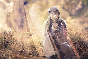shallow focus photography of girl blowing white Dandelion flower during dayime