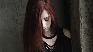 red haired girl in black cold-shoulder top leaning on wall