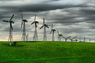 grey windmills on green grass field under cloudy sky