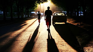 against the light photography of two person walking on road