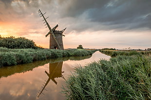brown windmill beside river during sunset