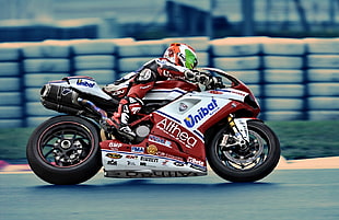 person in red racing suit on sports bike