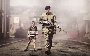 Soldier holding weapon beside boy on road