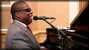 man wearing gray suit jacket paying piano