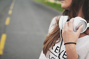 closeup photo of a girl standing on concrete road holding white wireless headset HD wallpaper