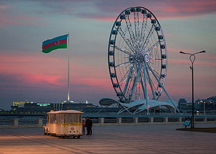 grey metal Ferris-wheel beside flag landmark