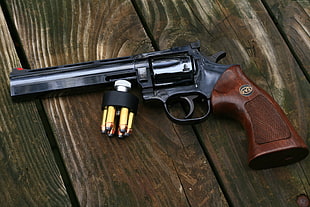 black and brown revolver gun on brown wood planks