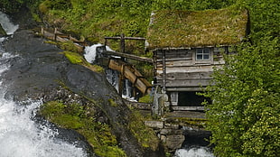 water flows near brown wooden house at daytime