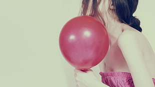 woman in pink strapless top holding red balloon