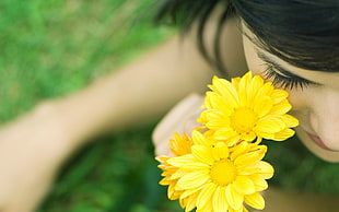 closeup photographt of woman near yellow daisy flowers