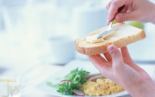 person holding bread and stainless steel knife