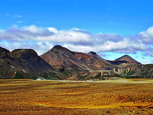 brown mountains near desert under blue and white sky, iceland