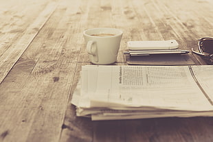 white ceramic cup, newspapers, coffee, smartphone, wooden surface