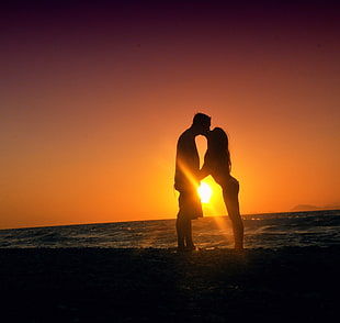 silhouette of man and woman kissing near the seashore during sunset HD wallpaper