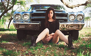 woman sitting in front of classic blue car