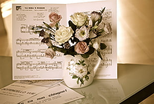 roses in white ceramic vase beside music note