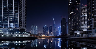 calm river between lighted high-rise building during nighttime