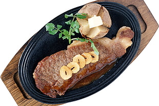 roast meat sliced and well cook potatoes on black oval sizzling plate