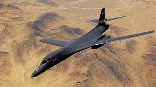 black fighting plane over gray desert during daytime