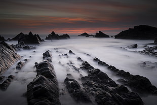 timelapse photography of rocky mountain covered by sea of clouds during sunset, hartland quay