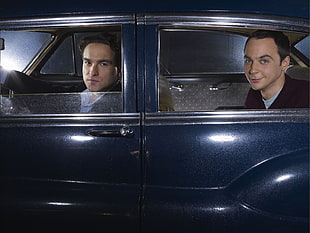 two man sitting inside car looking on camera smiling