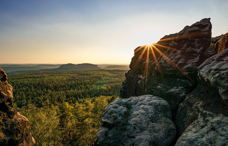 sun behind rock photo HD wallpaper
