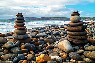 low angle photography of two piles of stones near seashore during daytime