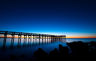 silhouette of wooden bridge on water at dawn HD wallpaper