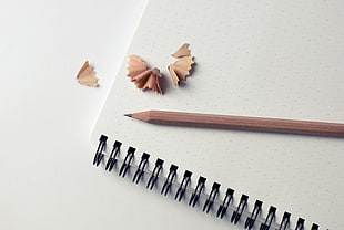brown sharpened pencil on white spiral notebook