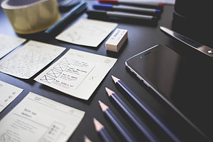 space gray iPhone 6 on table with pencils, printing paper, and scissors