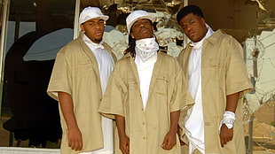three men wearing brown sports shirts, white bandannas, white fitted caps, and white shirts