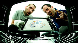 two men putting crate inside oven
