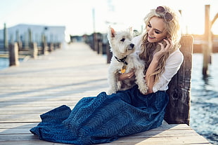 sitting woman in white dress and blue maxi skirt holding long-coated white dog