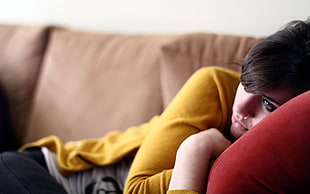 woman lying on brown sofa wearing yellow cardigan