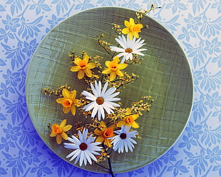 white and yellow petaled flowers on round green ceramic palte
