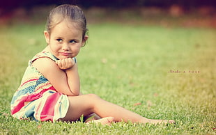 selective focus photography of girl sitting on grass field