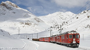 red train on trail covered with snow during daytime