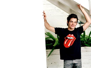 man wearing black Rolling Stones crew-neck t-shirt near white wall HD wallpaper