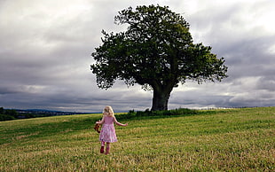 child wearing pink and white dress walking on green grass field