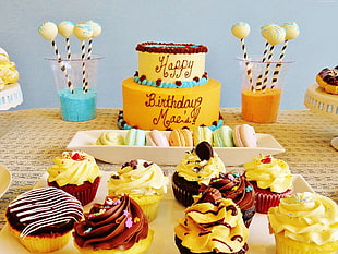 birthday cakes and cupcakes on top of table